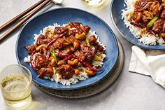 two blue plates filled with chicken and rice next to chopsticks on a table