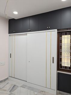 an empty room with white cabinets and black cupboards on the wall next to a window