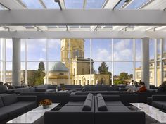 a large room with couches and tables in front of windows that look out onto the city