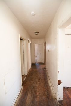 an empty hallway with wood floors and white walls