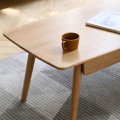 a wooden table with a cup on it and a book sitting on top of it