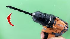 a cordless drill being held up by a hand with an arrow pointing towards it