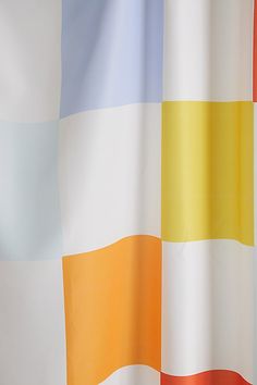 an orange, yellow and blue striped shower curtain with white trim on the bottom half