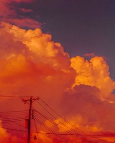 an orange sky with clouds and telephone poles in the foreground at sunset or dawn