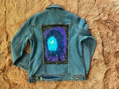 a blue jean jacket with an owl painted on it's back and stars in the sky