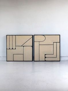 two abstract paintings on display in an empty room