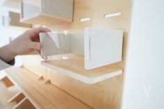 a person is holding a phone in front of some wooden shelvings and shelves