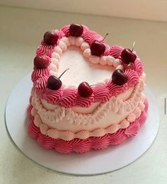 a pink and white cake with cherries on top