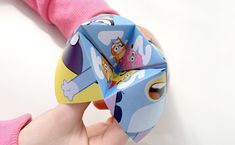 a person holding a toy with cartoon characters on it's face and the hands