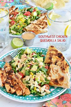 a plate with chicken, salad and pita bread on it sitting on a table