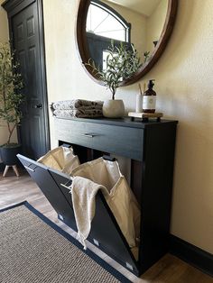 an entryway with a mirror, plant and towels on the table in front of it