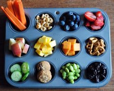 a muffin tin filled with lots of different types of fruit and veggies