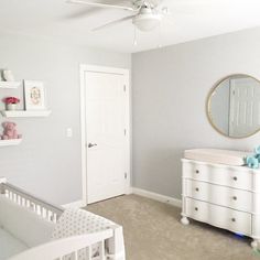 a baby's room with a crib, dresser and mirror on the wall