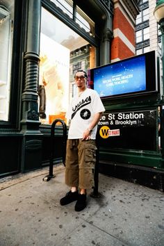 a man standing on the sidewalk in front of a sign that says st station and brooklyn