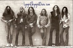 an old black and white photo of five men with long hair standing in front of a wall