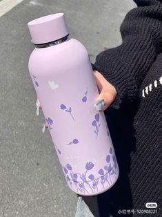 a person holding a purple water bottle in their left hand and wearing a black sweater