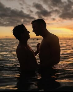 two men standing in the water facing each other with their faces close to one another