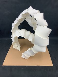 a sculpture made out of white paper sitting on top of a cardboard box