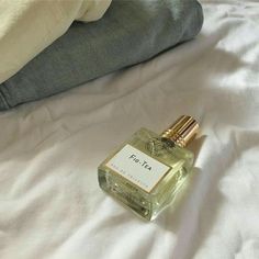 a small bottle of perfume sitting on top of a bed next to a person's leg