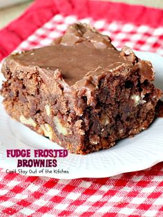 a piece of fudge frosted brownies on a plate with a red and white checkered tablecloth