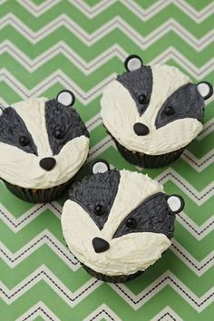 three cupcakes with black and white frosting decorated like raccoon faces