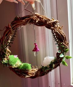 someone is holding up a wreath made out of twigs and branches with flowers on it