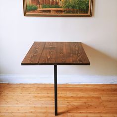 a wooden table sitting on top of a hard wood floor next to a white wall