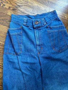 This pair of vintage h.i.s. Brand bellbottom jeans have a zipper with unique button closure.  The pockets have rays coming out with orange topstitching.  There is wear and fading as shown in pictures.  Waist-26 inches Hips-37 inches Rise-11.5 inches Inseam-32 inches Waistband-2 inches wide Belt loops-1.5 inches Thigh-20 inches Knee-21 inches Bell-23 inches To see more of our authentic 70's vintage clothing inventory please visit our store at ChoiceRecycling.  We add new items every week. Retro High Rise Flare Jeans With Button Closure, Retro High Waist Bottoms With Five Pockets, Retro High Waisted Bottoms With Five Pockets, Retro Wide Leg Jeans With Button Closure, Vintage Wide Leg Jeans With Pockets, Retro Mid-rise Jeans With Pockets, Retro Denim Blue Flare Jeans With Five Pockets, Retro Denim Flare Jeans With Pockets, Retro Flare Jeans With Five Pockets In Denim Blue