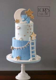 a blue and white baby shower cake with stars on the top is decorated with a teddy bear