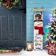 a snowman is standing in front of a door with a sign that says home sweet place to be