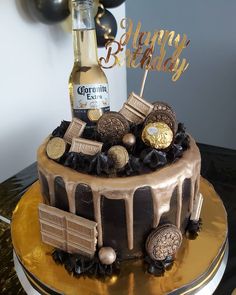 a birthday cake decorated with chocolates and gold decorations, along with a bottle of champagne