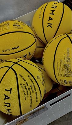 several yellow basketballs are stacked in a box