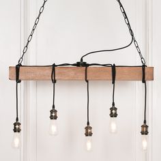 a light fixture with five bulbs hanging from it's wooden beam and some wire