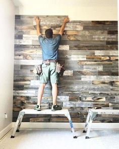 a man standing on top of a step ladder in front of a wooden paneled wall