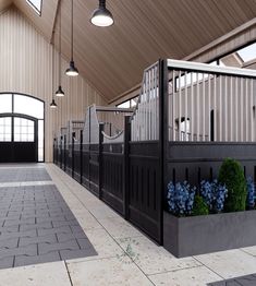 the inside of a horse stable with blue flowers on the floor and black railings