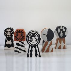 five wooden sculptures are lined up in a row on the floor, one is painted black and white