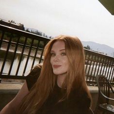 a woman with long red hair sitting on a bench