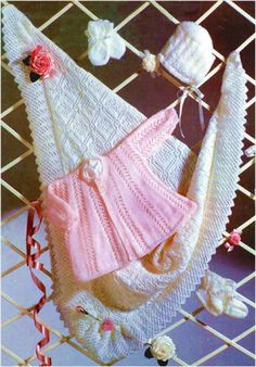 a crocheted baby's dress and hat hanging on a clothesline with flowers