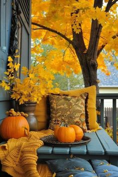 two pumpkins sitting on a blue bench in front of a tree with yellow leaves