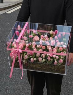 a man holding a clear box filled with pink flowers