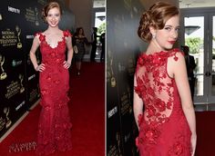 a woman in a red dress on the red carpet at an awards event with her hair pulled back