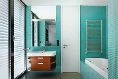 a bathroom with blue tiles and a white bathtub next to a wooden sink vanity