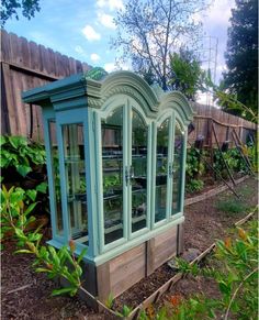 an old china cabinet sitting in the middle of a garden