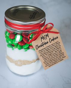 a jar filled with white and green candies next to a tag that says metm