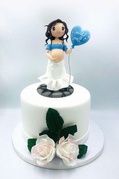 a white cake with a figurine holding a blue balloon and flowers on top