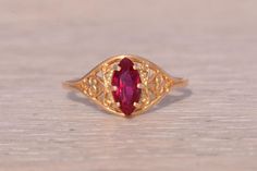 This stunning piece, known as The Classic Filigree, features a captivating marquise cut lab created ruby at its center. The ruby is elegantly set in intricate filigree detailing crafted in 14 karat yellow gold, adding a touch of timeless sophistication. The ring is currently a finger size 6 but can be adjusted to any finger size for an additional charge upon request, ensuring a perfect fit. Love this piece, but don't have the money to spend right now? We offer FREE layaway on every item in our shop. With just 20% down, take one full year (interest-free) to pay off your new jewelry! There are no hidden fees or charges, ever. For more information on our layaway policy, please contact us. Each piece has been hand-selected and meticulously identified and graded by a Graduate Gemologist who has Elegant Yellow Gold Ruby Ring With Intricate Design, Elegant Marquise Ruby Ring With Diamond Cut, Elegant Red Marquise Ruby Ring, Elegant Marquise Cut Ruby Ring, Gold Marquise Ruby Ring, Marquise Ruby Ring In Gold, Marquise Ruby Ring As Birthstone, Ornate Gold Ruby Ring, Marquise Ruby Ring With Birthstone