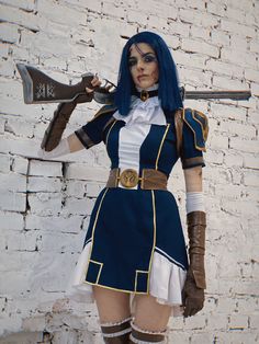 a woman dressed in blue and white is holding two large metal axes while standing next to a brick wall