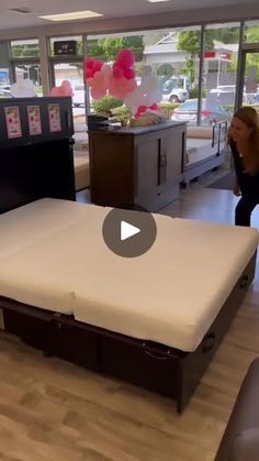 a woman standing in front of a bed with a mattress on the bottom and side