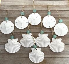 six seashell ornaments hanging from string on wooden plank with sea glass bead necklaces