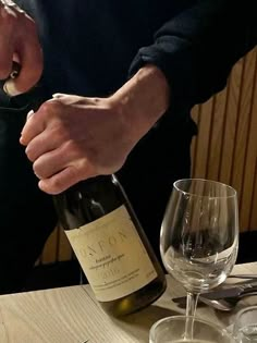 a man pouring wine into a glass on top of a wooden table with utensils